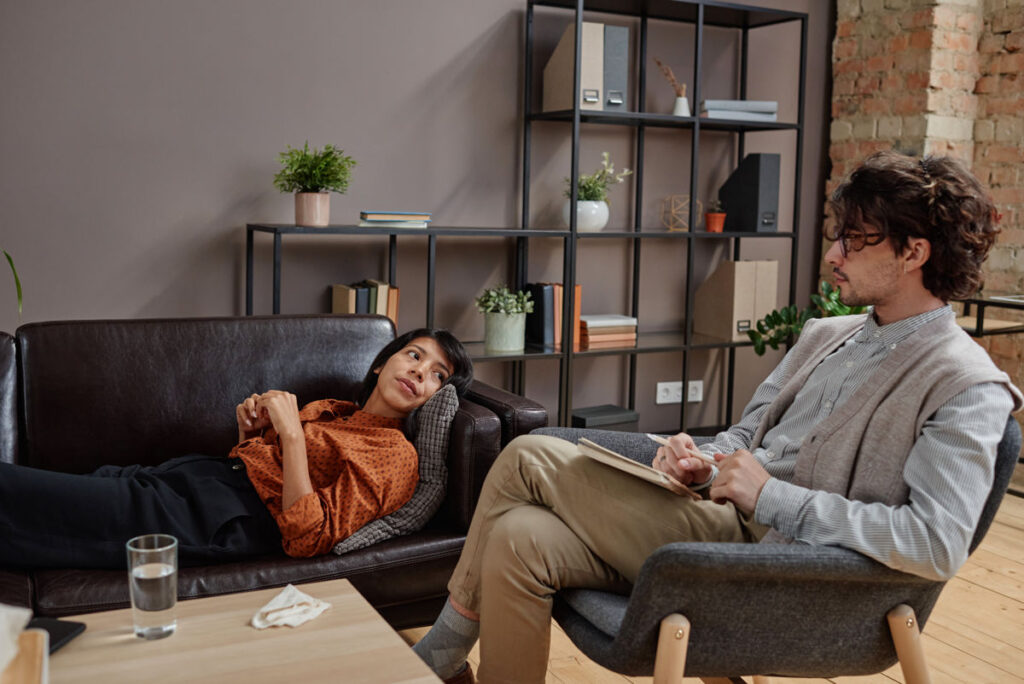 Horizontal shot of modern professional psychotherapist working with depressed young woman doing psychoanalysis