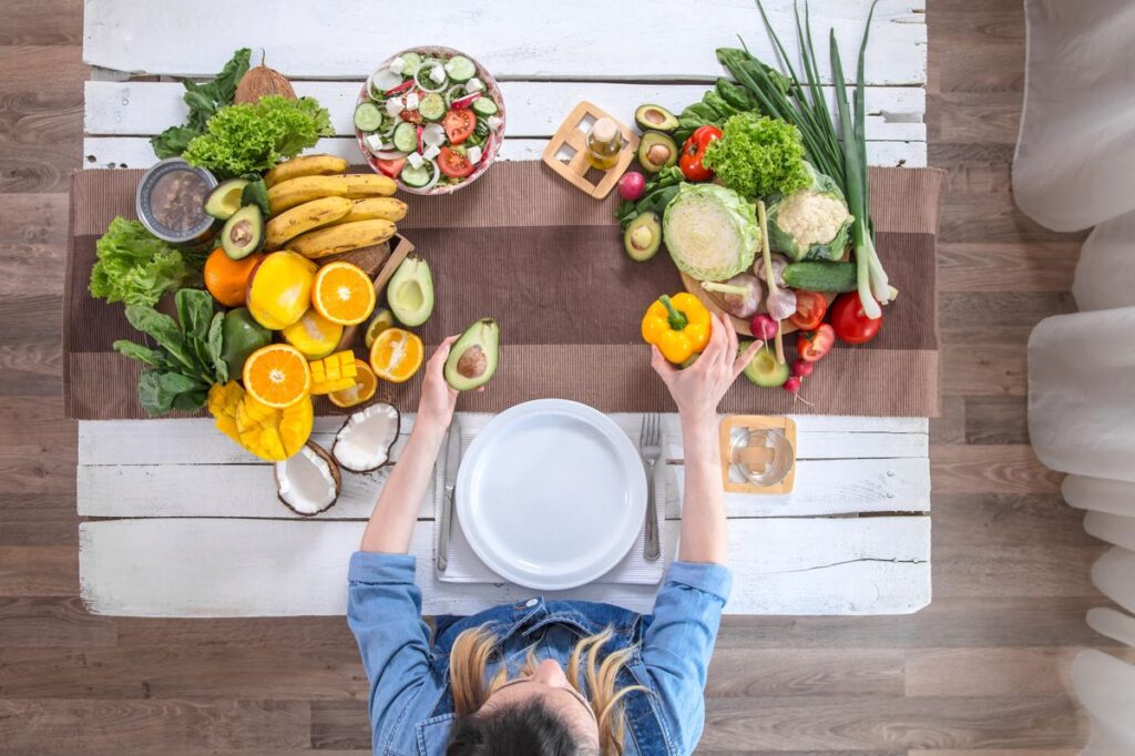 Woman at the dining table with a variety of organic healthy food , top view. The concept of healthy eating and celebration