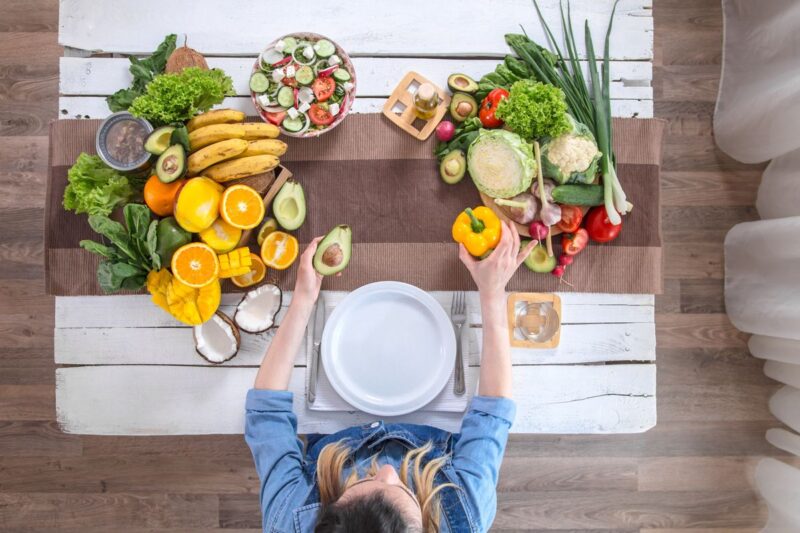 Woman at the dining table with a variety of organic healthy food , top view. The concept of healthy eating and celebration