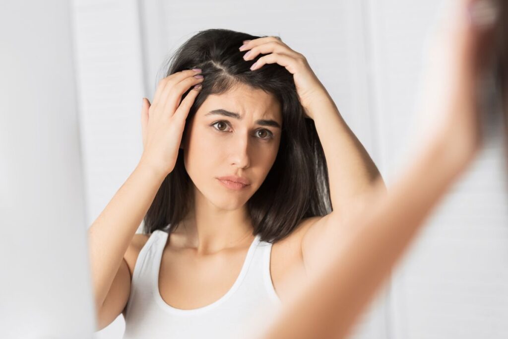 Hair loss Problem. Brunette Girl Looking At Hair Flakes In Mirror Standing In Bathroom. Panorama, Selective Focus